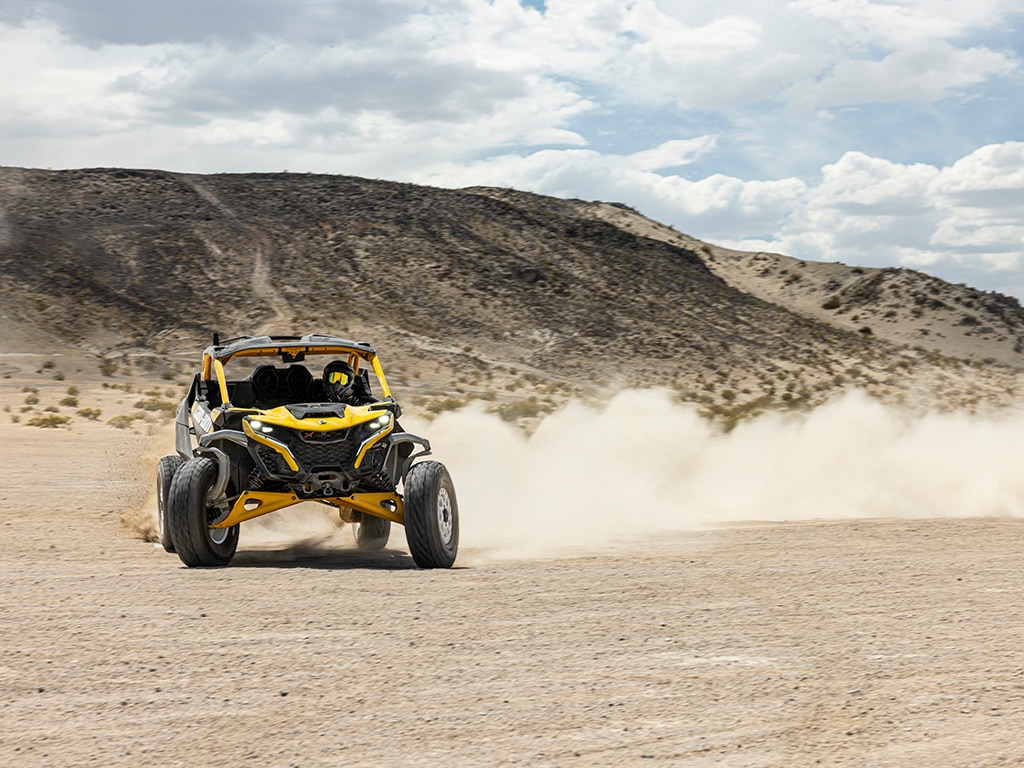 Voznik, ki v puščavi vozi vozilo Can-Am Maverick R SxS letnik 2024