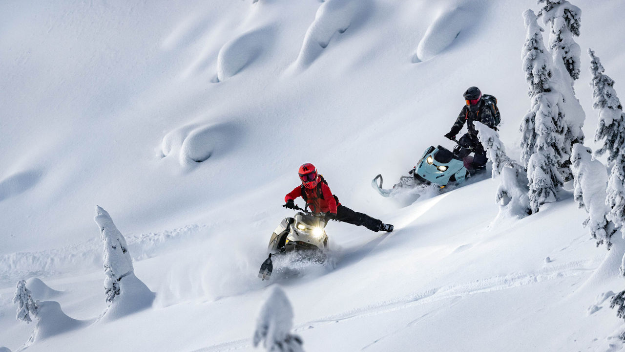 Dvaja jazdci riadia ich Ski-Doo deep snow skúter v horách