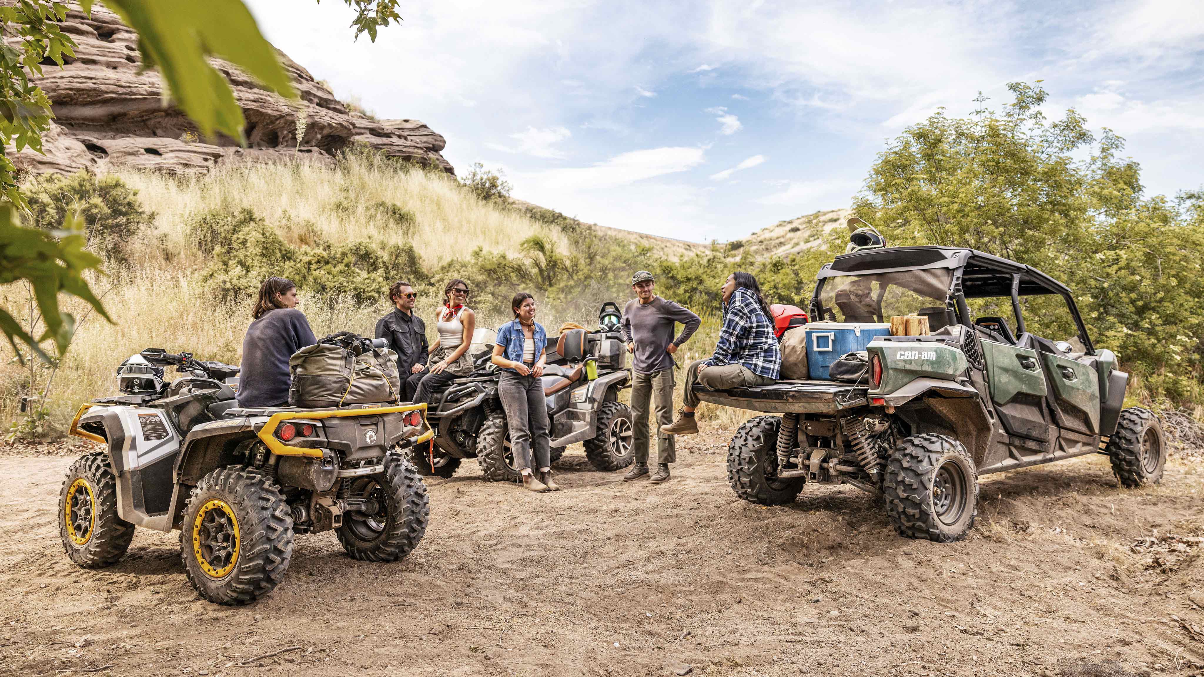Μια ομάδα αναβατών κάνει ένα διάλειμμα στην έρημο δίπλα στα οχήματα Can-Am ATV και SxS.