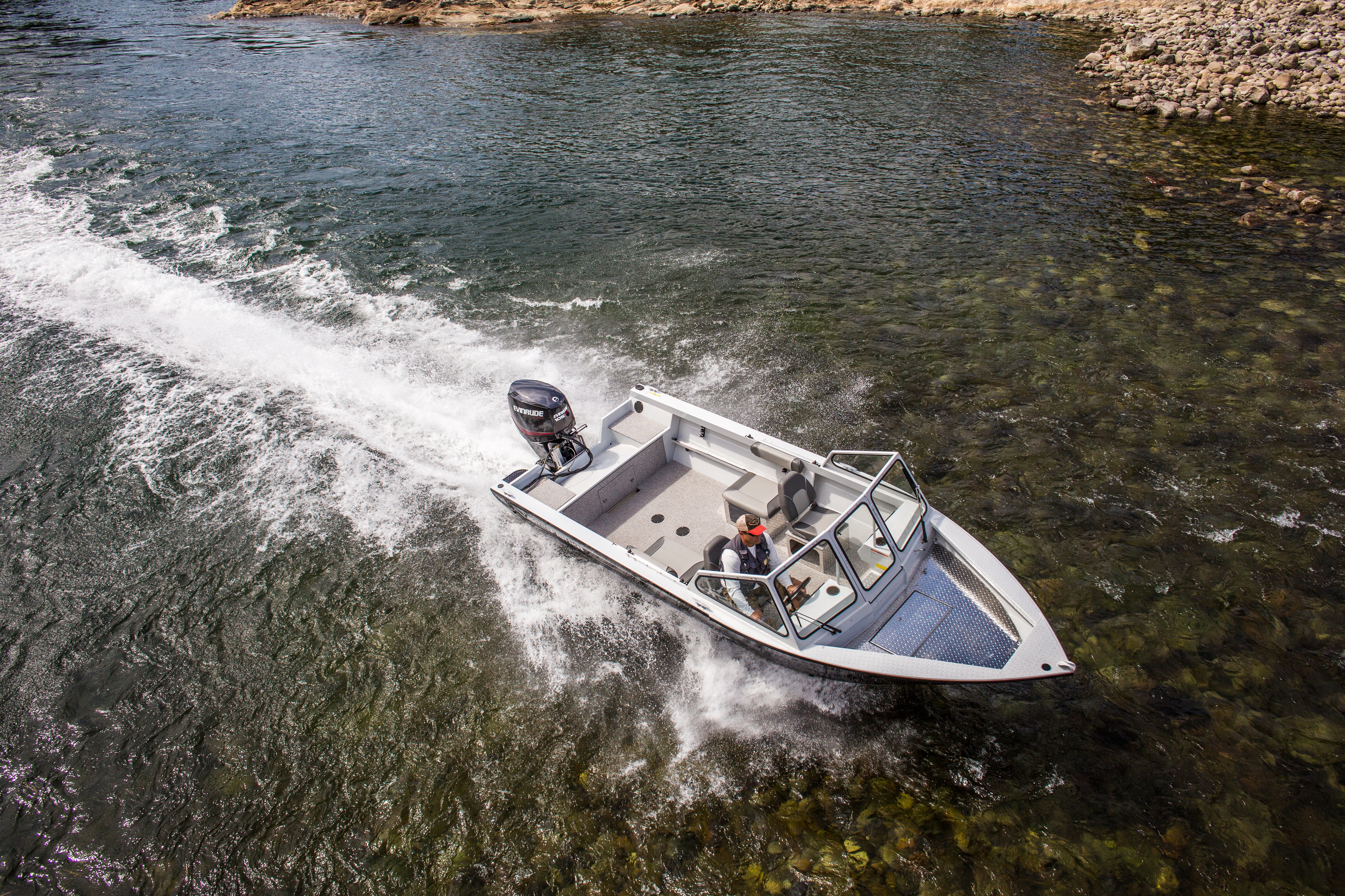Man driving a Evinrude motorboat in shallow water
