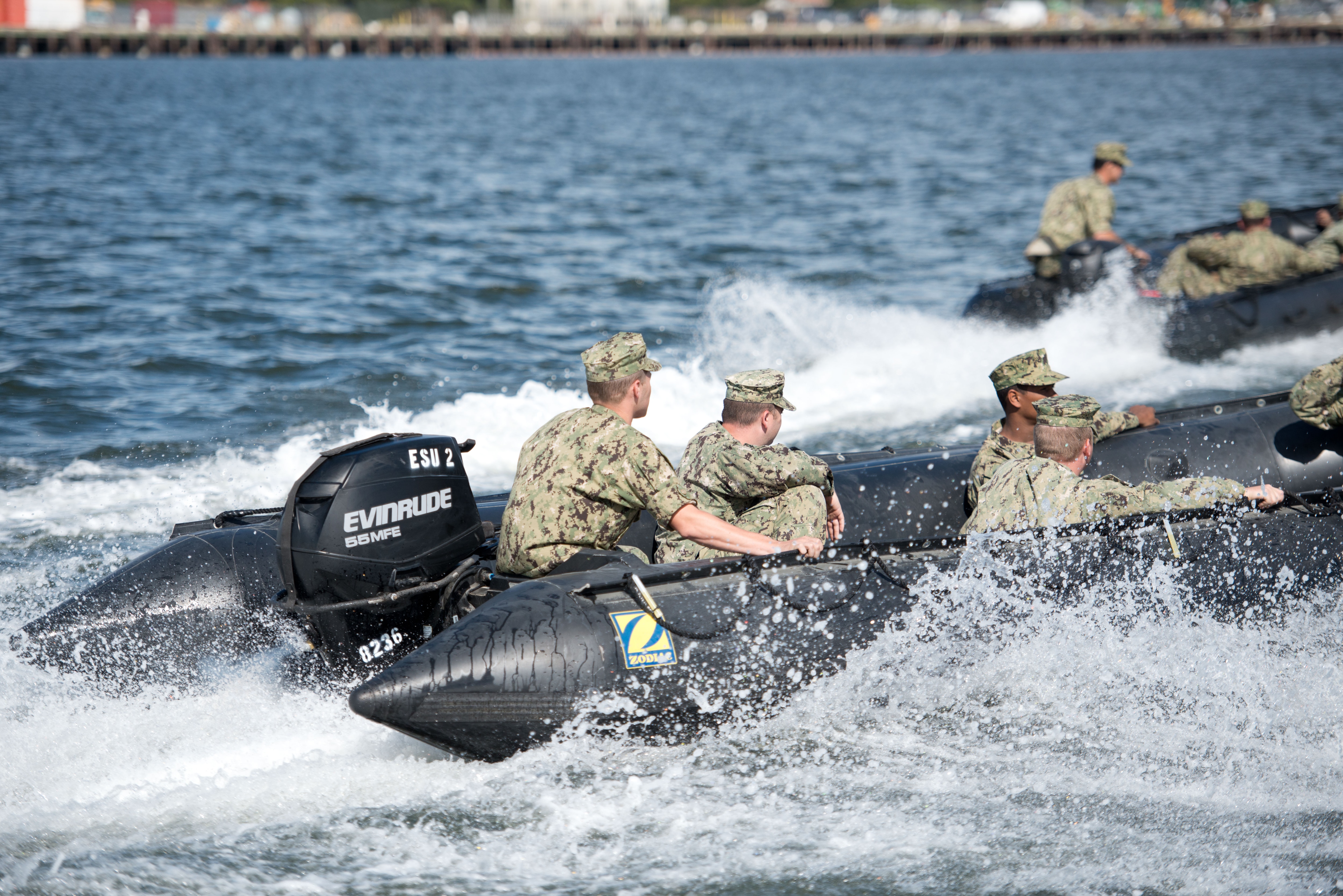 Military personnel in a boat yielding an Evinrude motor