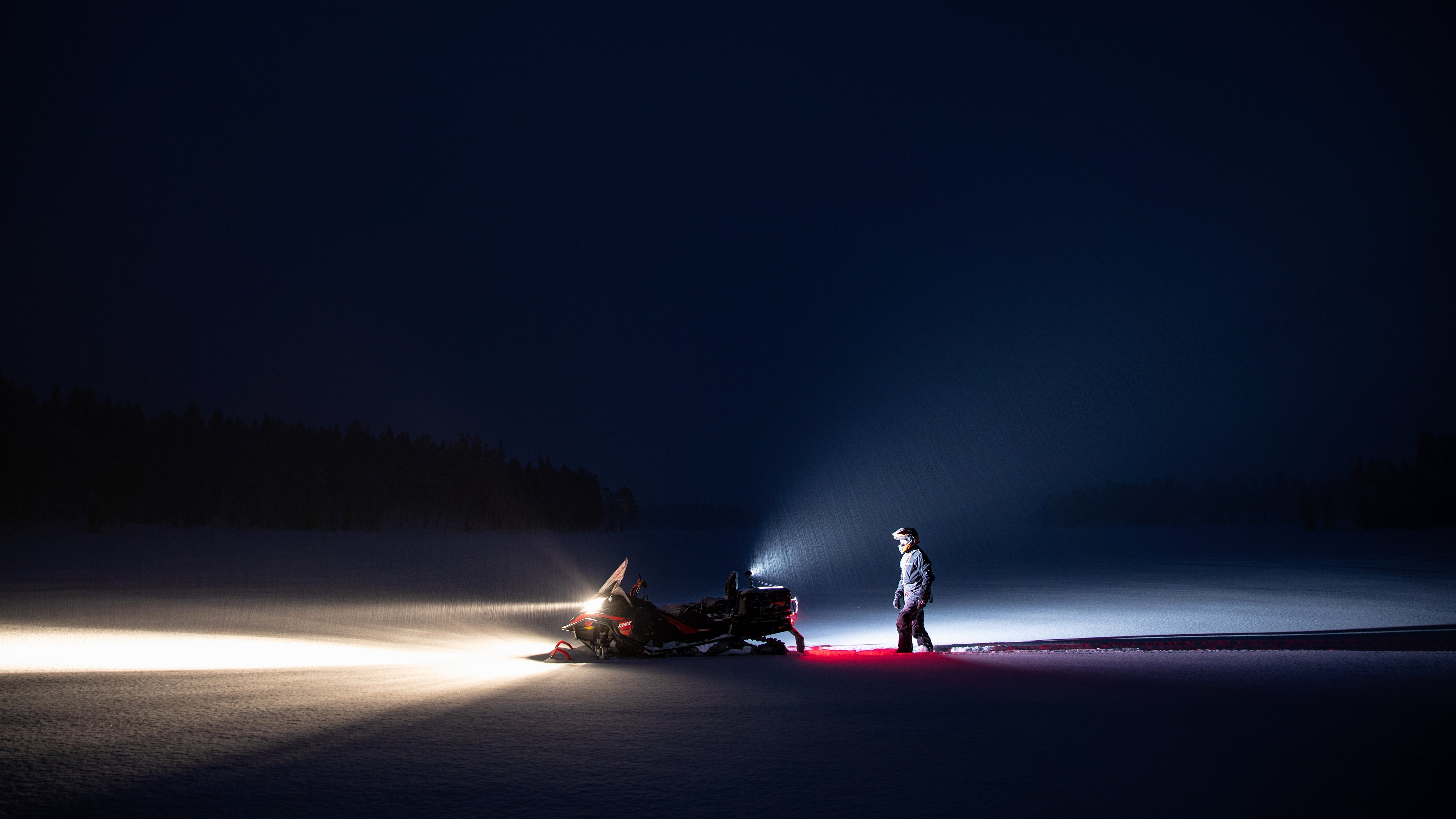 Wide shot ενός άνδρα που περπατάει προς το lynx όχημα χιονιού 2021  το βράδυ 
