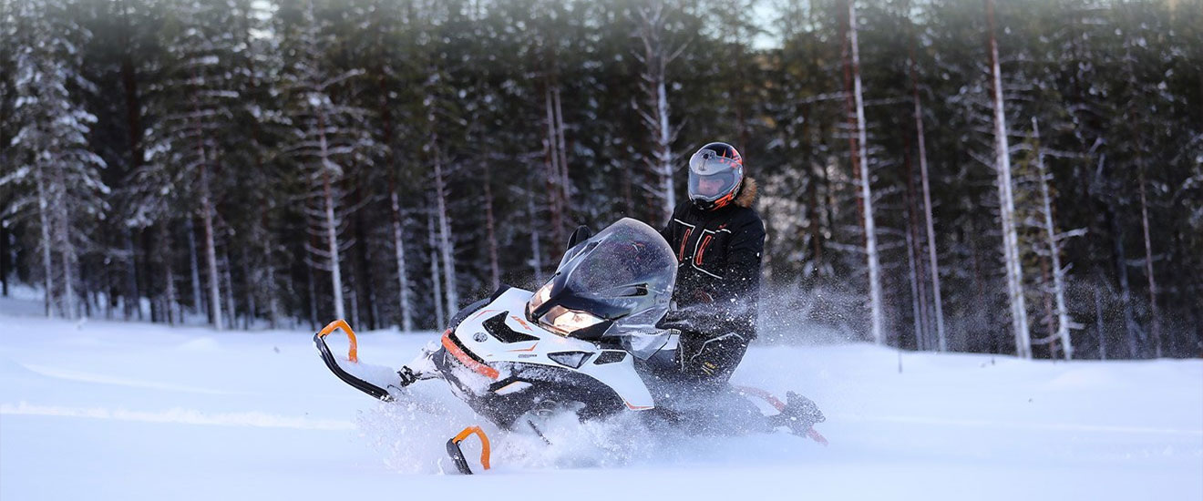 Man driving his 69 Ranger snowmobile through snow