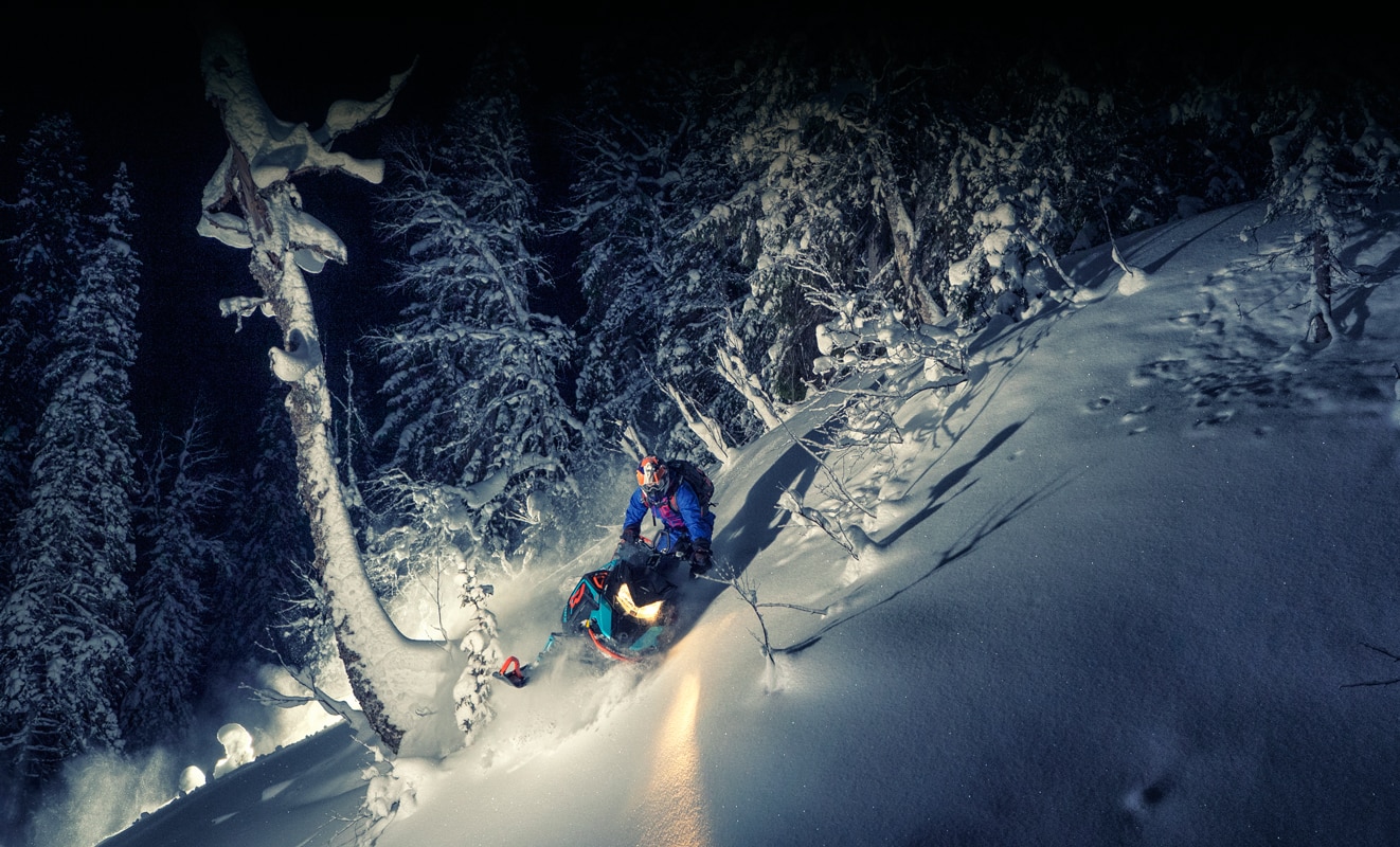 Čovjek tokom noći čvrsto skrene na snježnom brdu sa svojim modelom Lynx Boondocker 3900