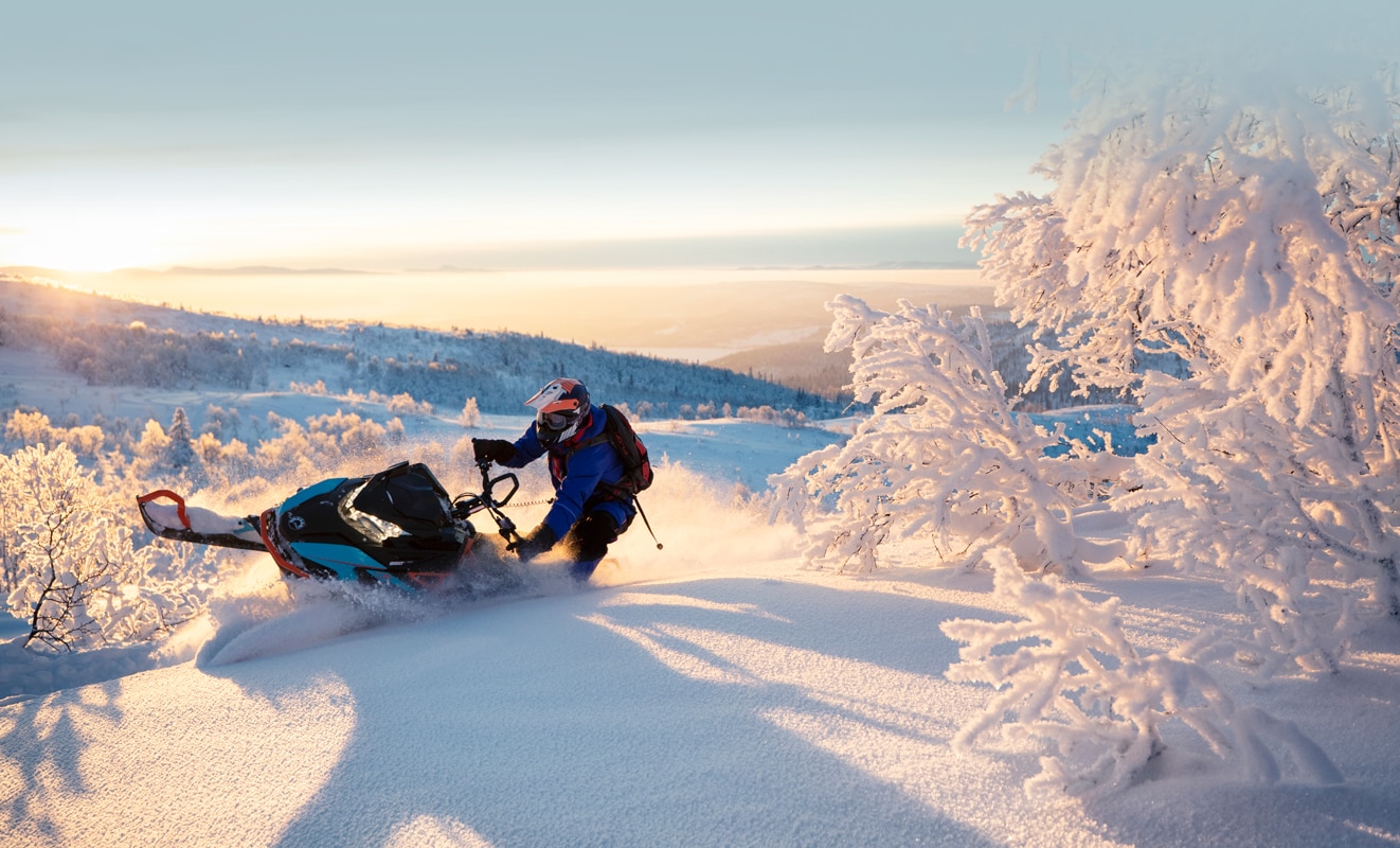  Čovjek čvrsto zavija na snježnom brdu sa svojim modelom Lynx Boondocker 3900 pri zalasku sunca