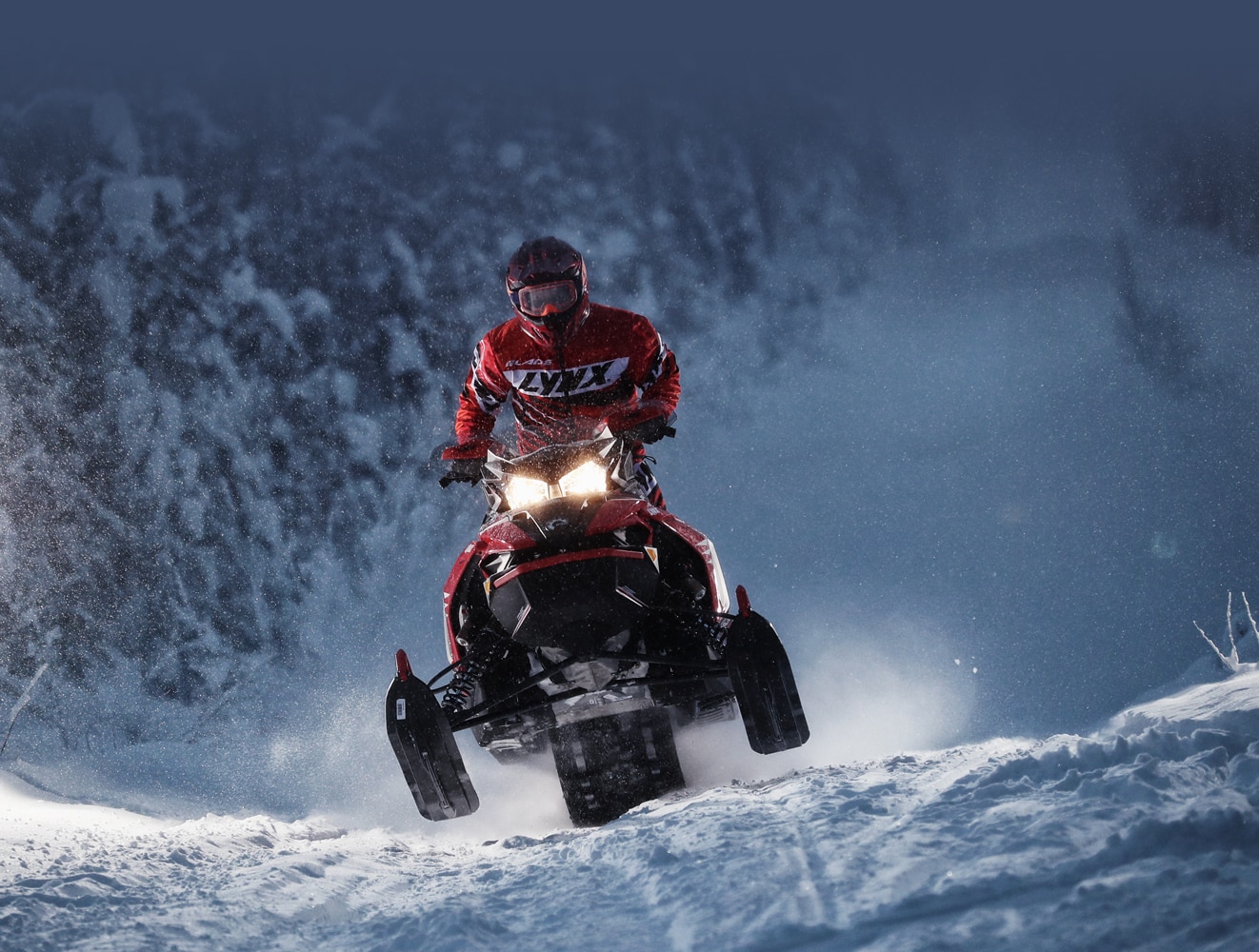 A man is riding his Lynx Rave Re Snowmobile Model at high speed during the night