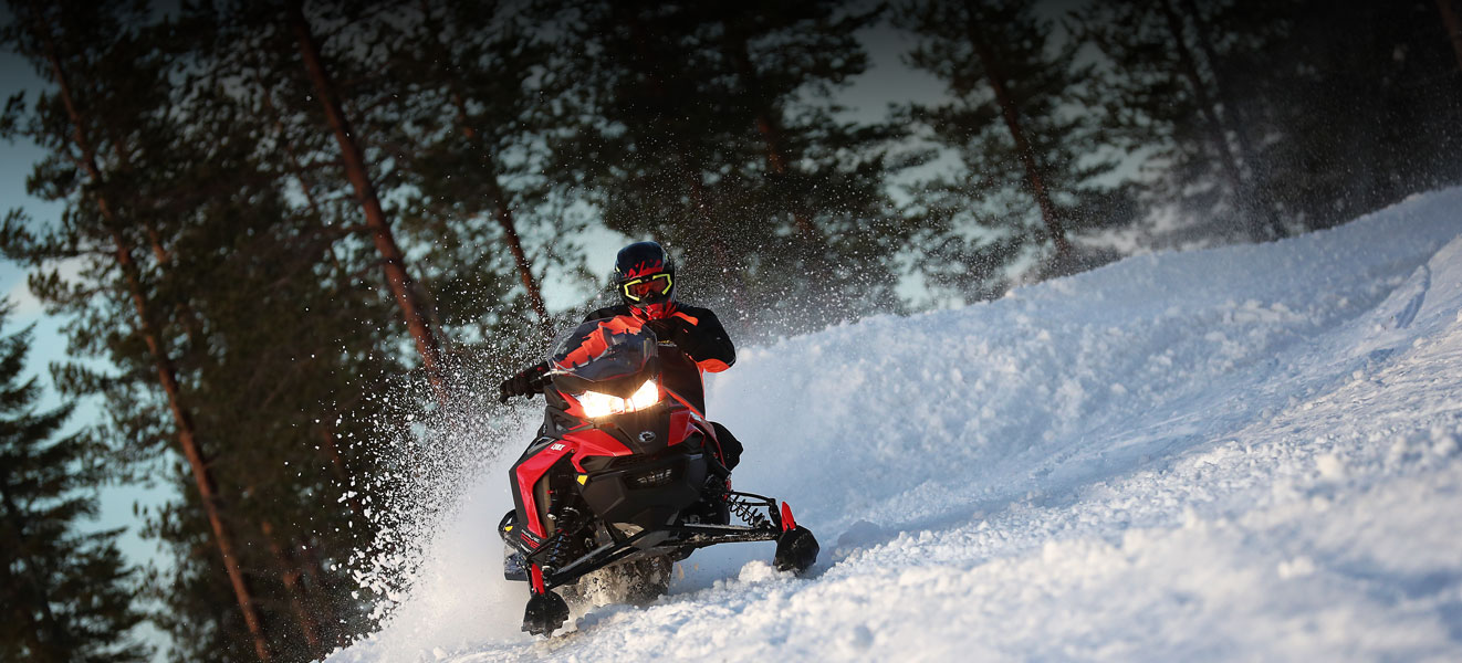 A man is riding his Lynx Rave Re Snowmobile Model at high speed 