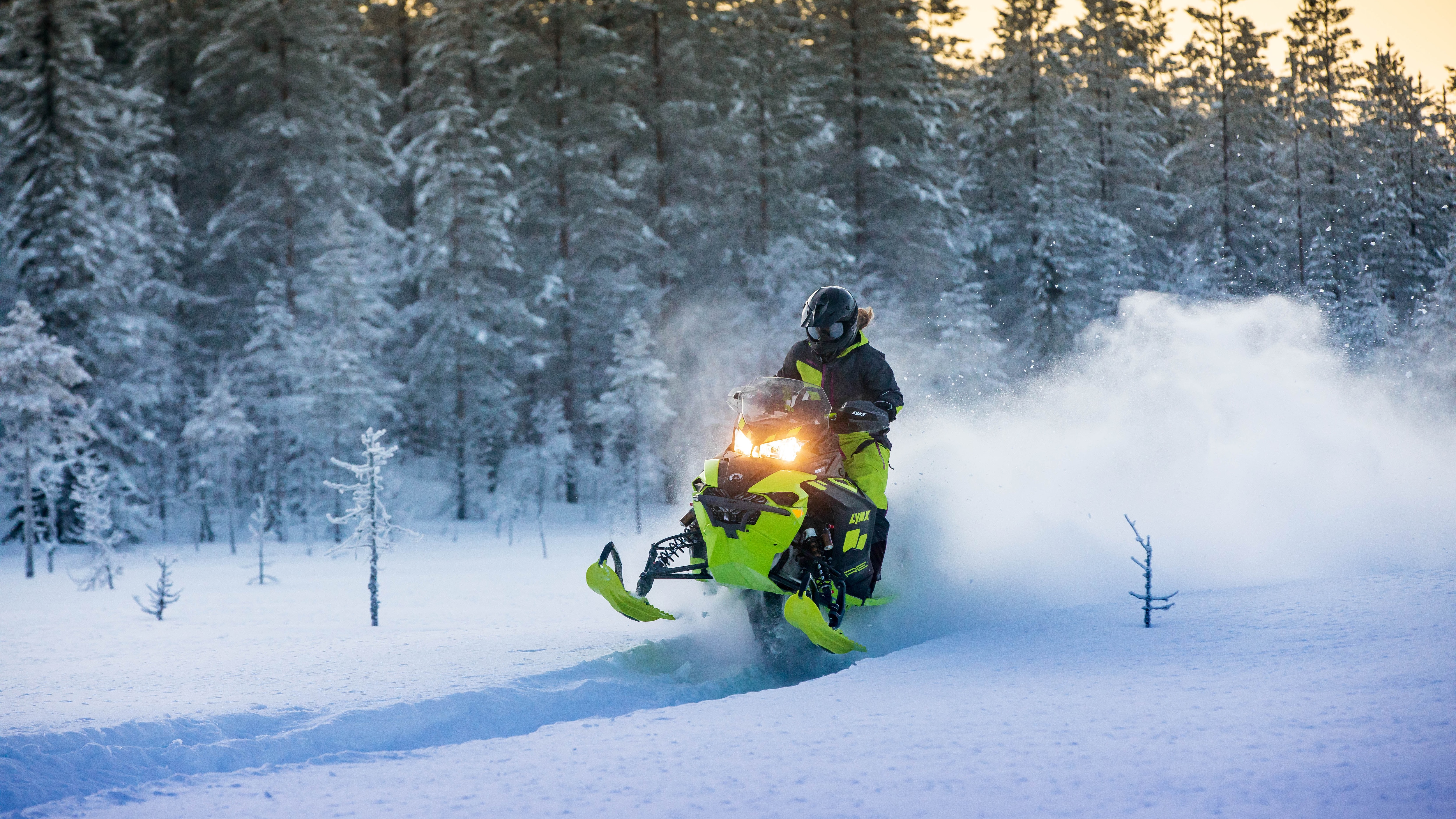 Motorschlitten-Fahrer, der mit seinem Lynx durch Schneelandschaft fährt