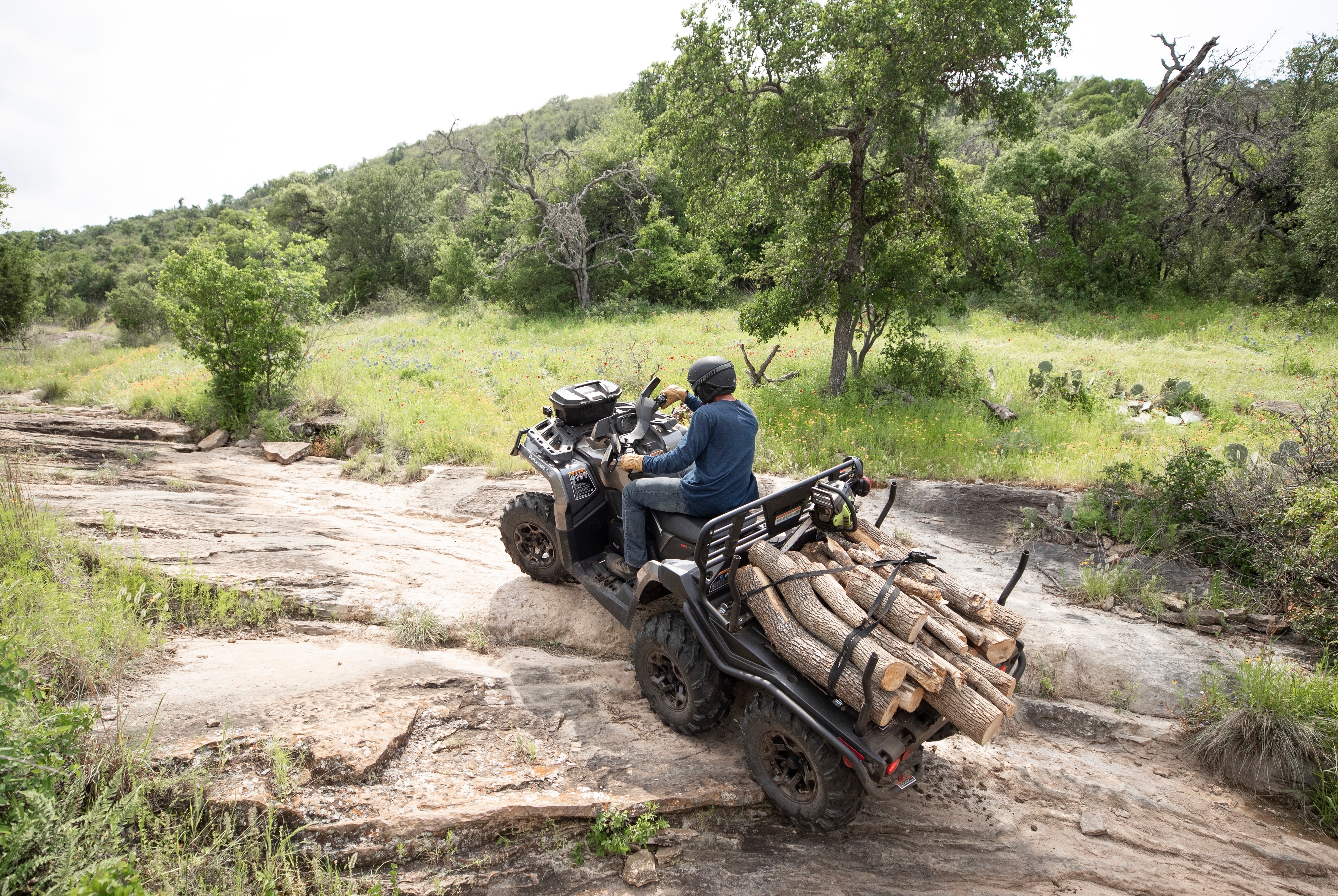  Čovjek vozi svoj Outlander Max uz malo brdo dok je na poleđini svog ATV-a nosio drva