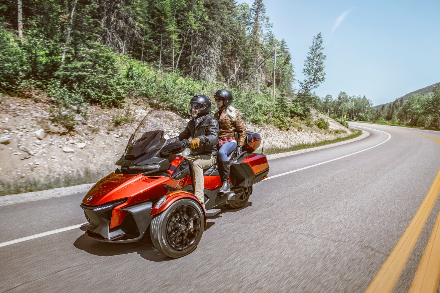 Right angle view of a couple driving a Can-Am Spyder RT on a scenic road