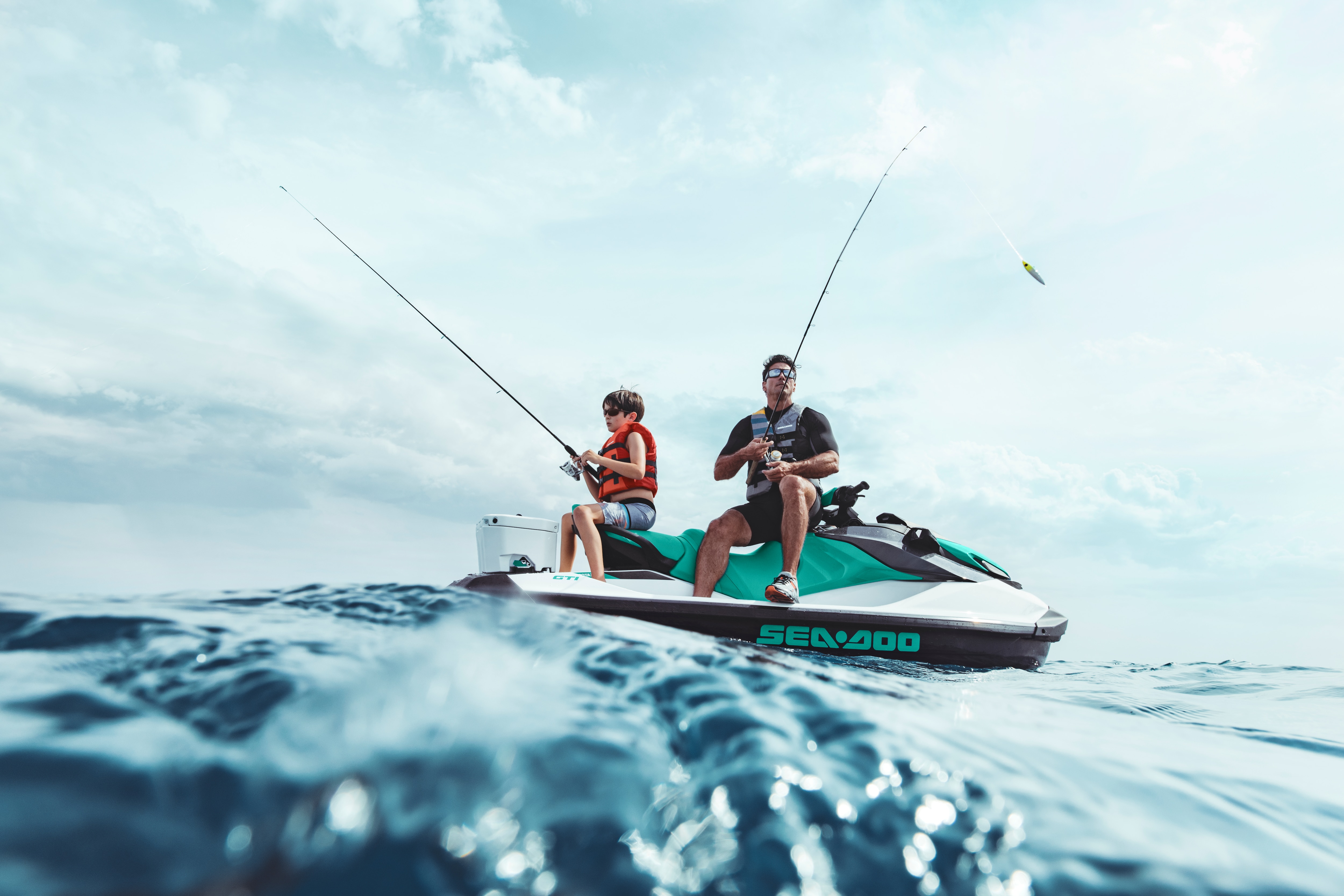 Man and kid fishing while sitting on a Sea-Doo GTI