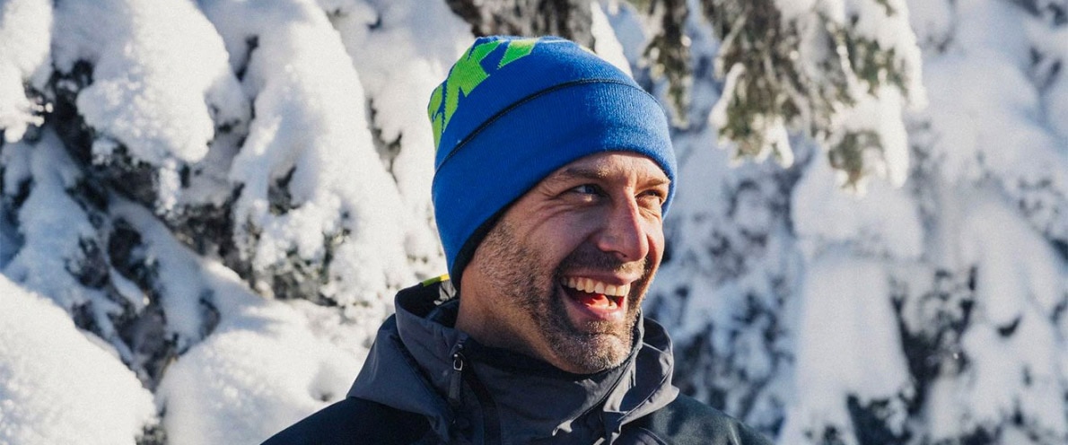  Foto e njeriut duke buzëqeshur pranë një pylli me dëborë