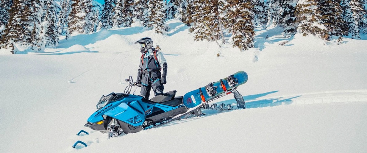  Čovjek u blizini svog Ski-Doo samita i svog snowboarda