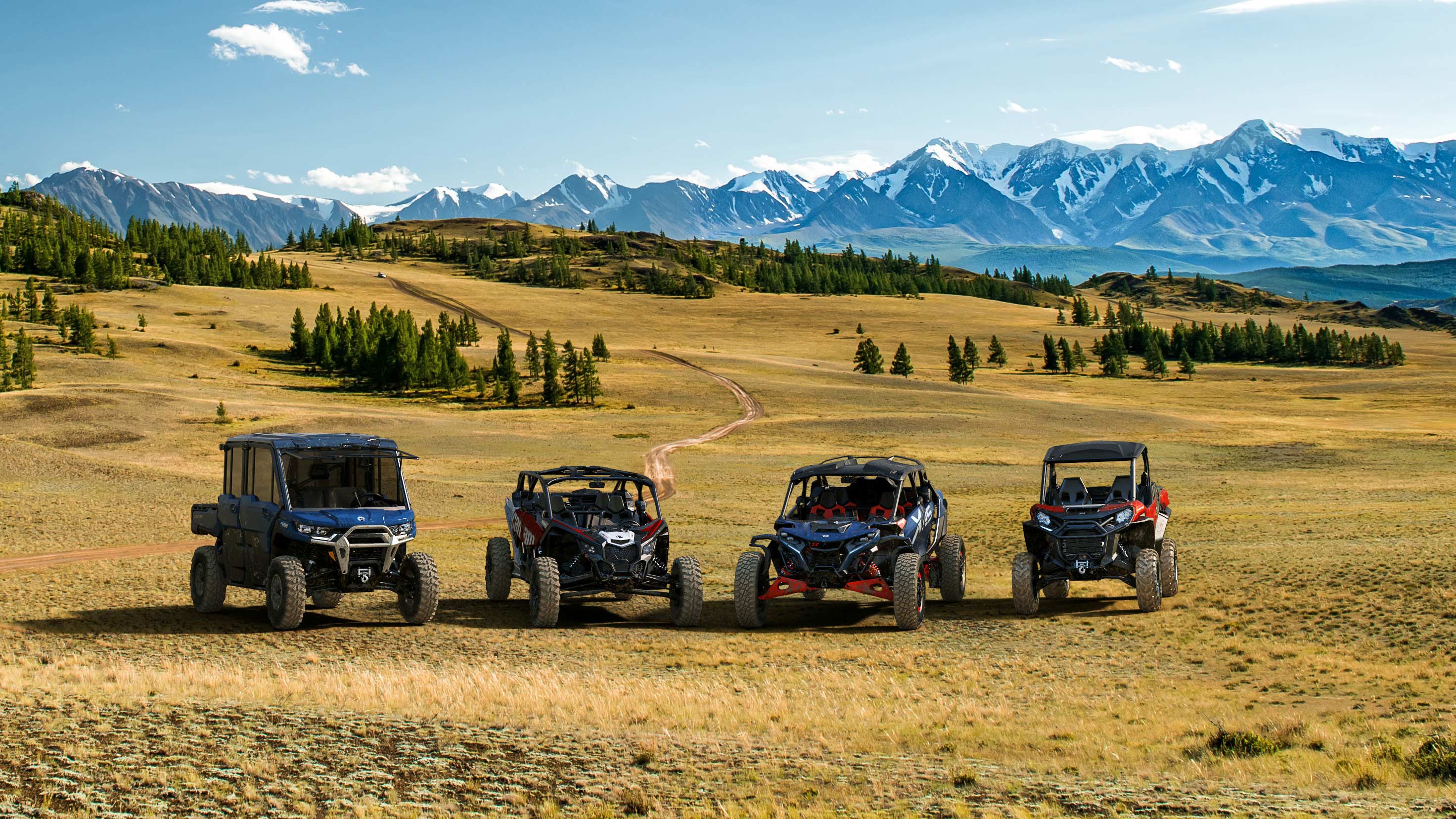 The Can-Am SSV family, next to each other, in front of a vast, mountain-studded terrain