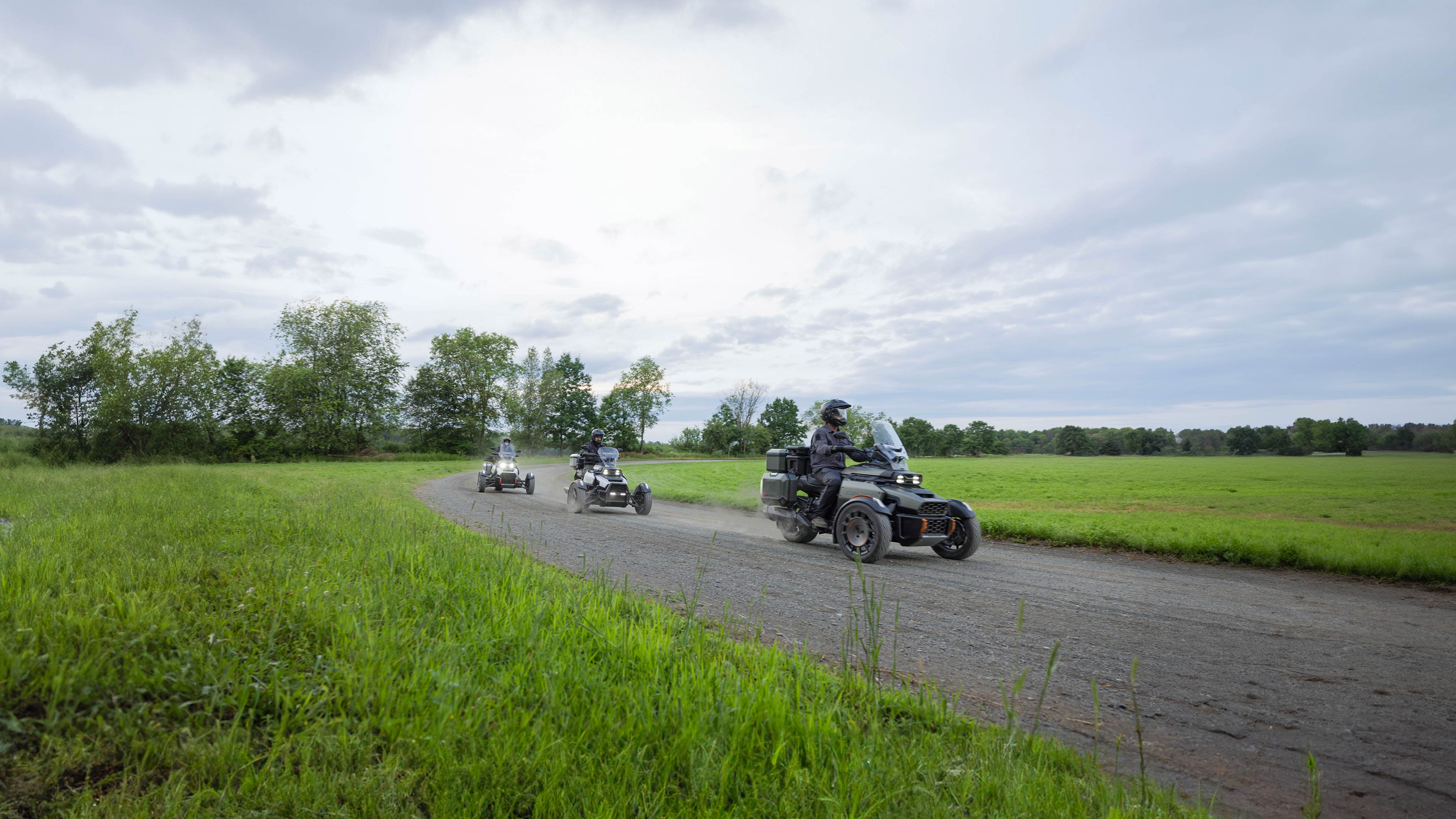 Three Can-Am 3-wheelers following each other on an unpaved road