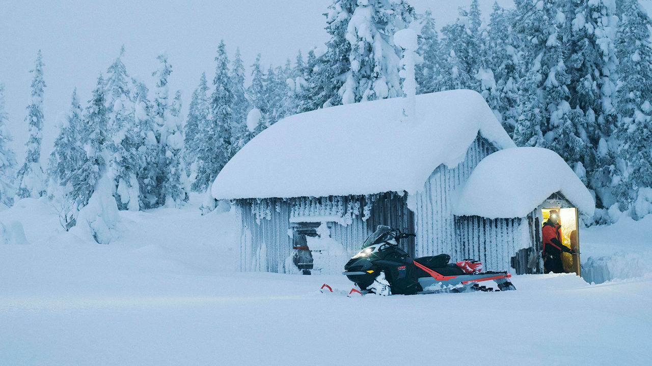 49 Ranger PRO snežný skúter zaparkovaný pred chatou v lese