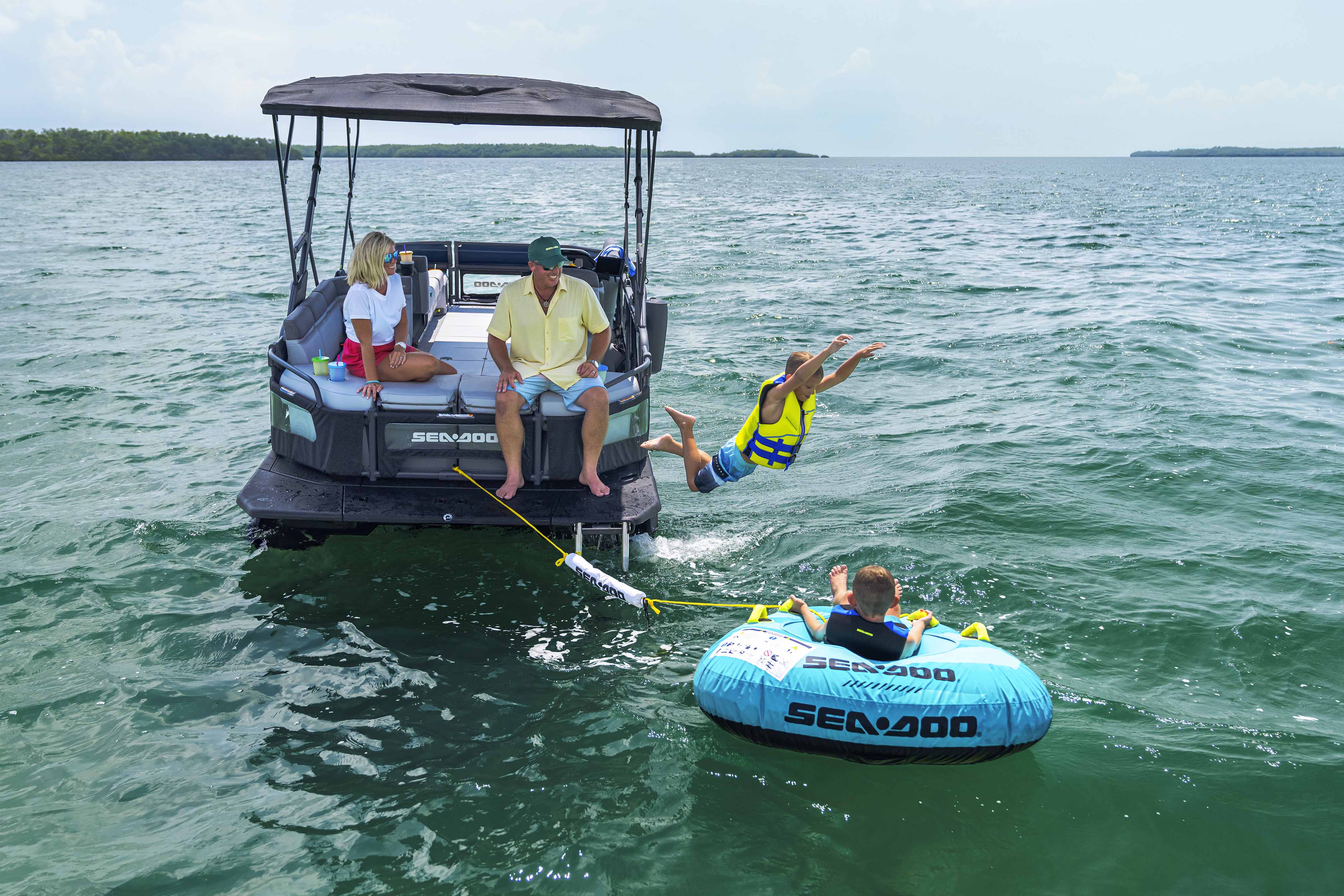 Family enjoying tubing with their 2024 Sea-Doo Switch Cruise pontoon