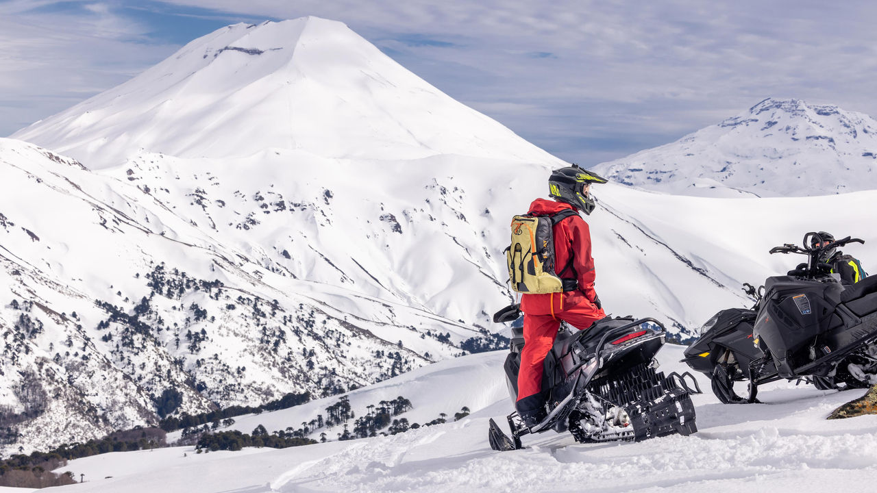 Muž stojí na svojom Ski-Doo na vrchole hory v Chile