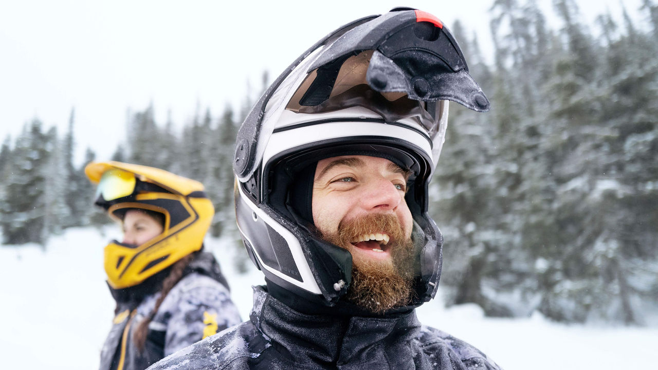 Dvaja jazdci v oblečení Ski-Doo na traili