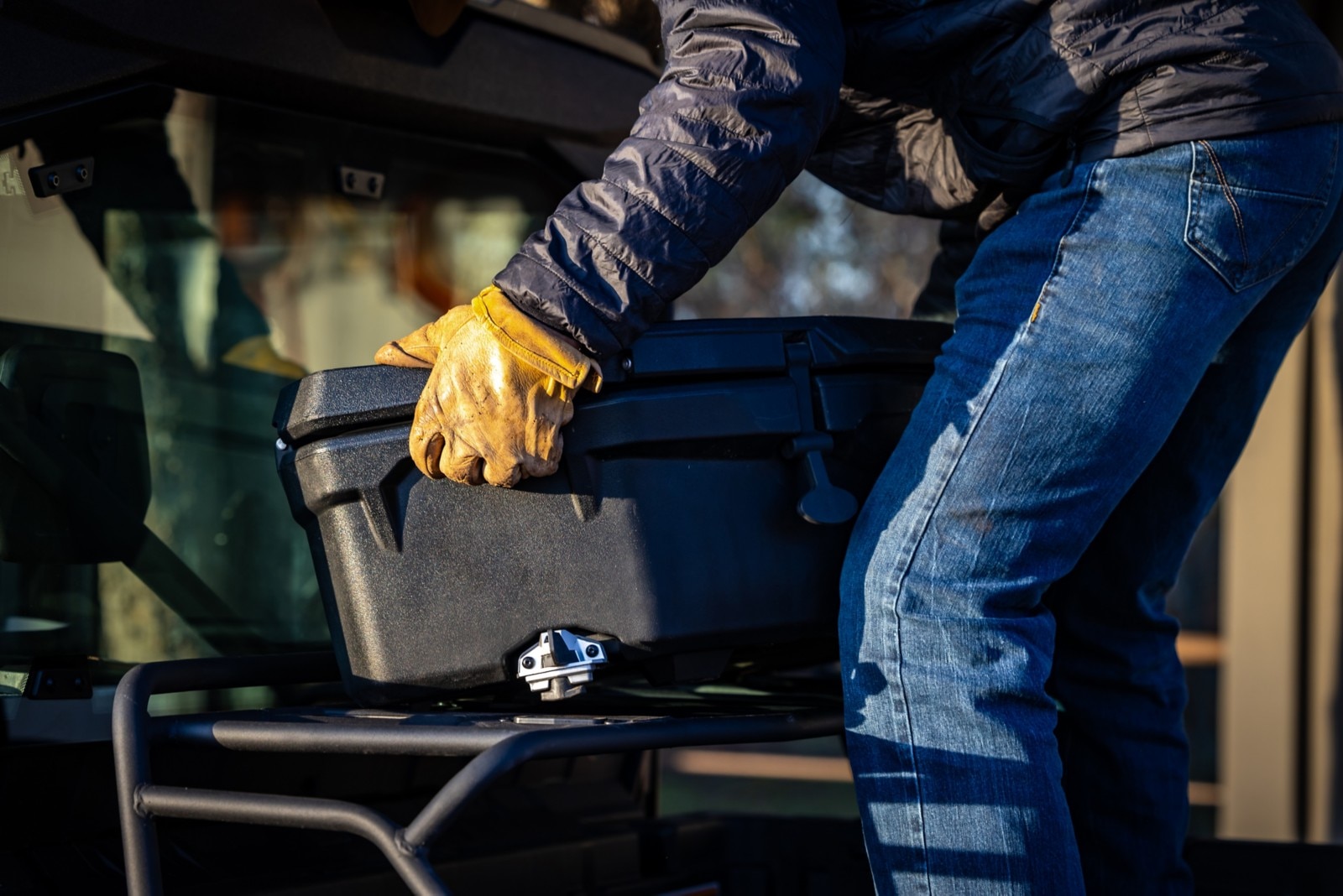 A worker wearing gloves, installing a LinQ Cargo box in the bed of his Defender Lonestar CAB